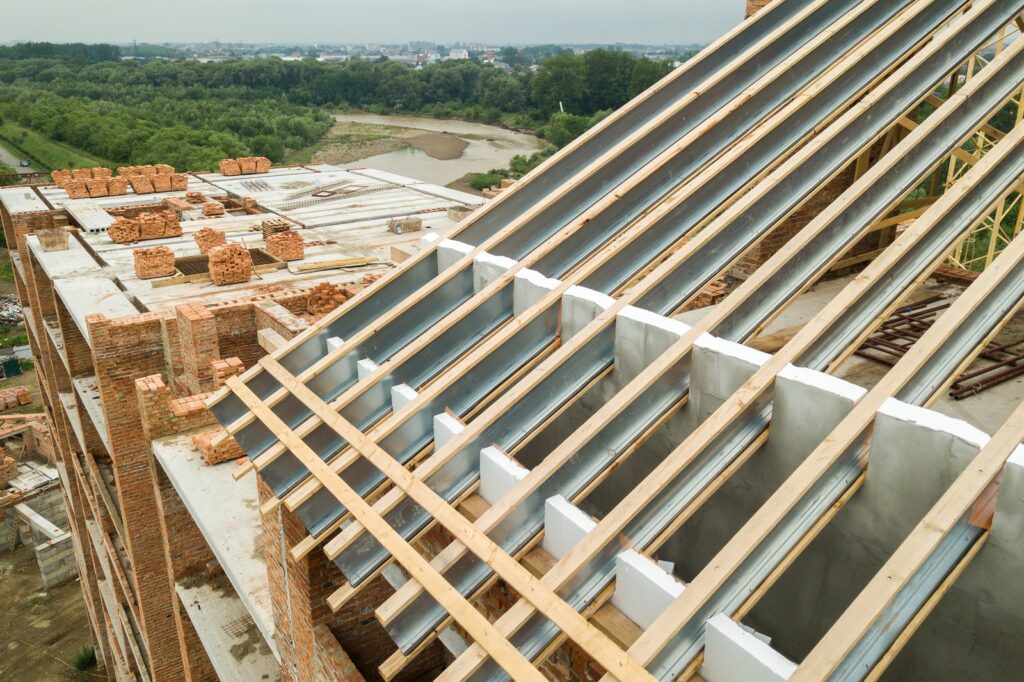 Metal Roof Framing Installation With Wooden Trusses On Large Residential Building Construction